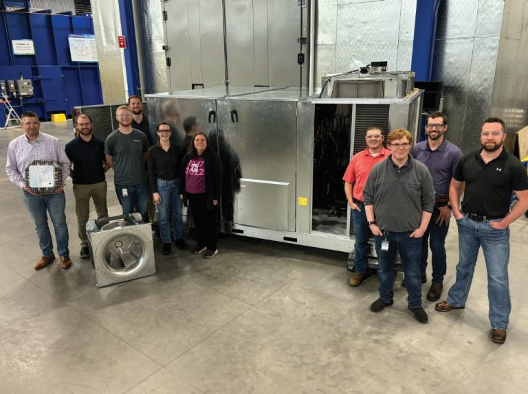 group of people standing by manufacturing equipment